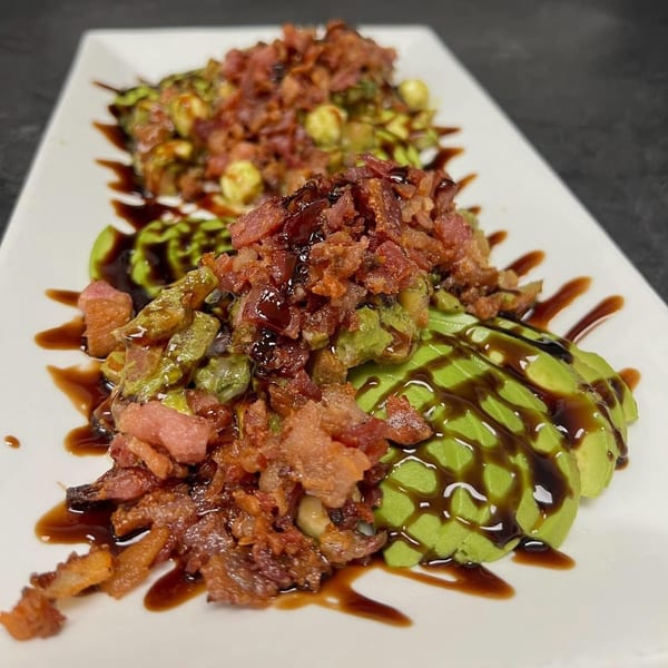 Two servings of sliced avocado and Brussels sprouts topped with bacon and balsamic glaze.